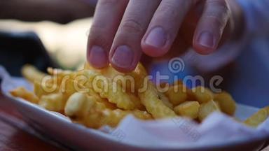 手从盘子里拿起炸土豆。 模糊的特写。
